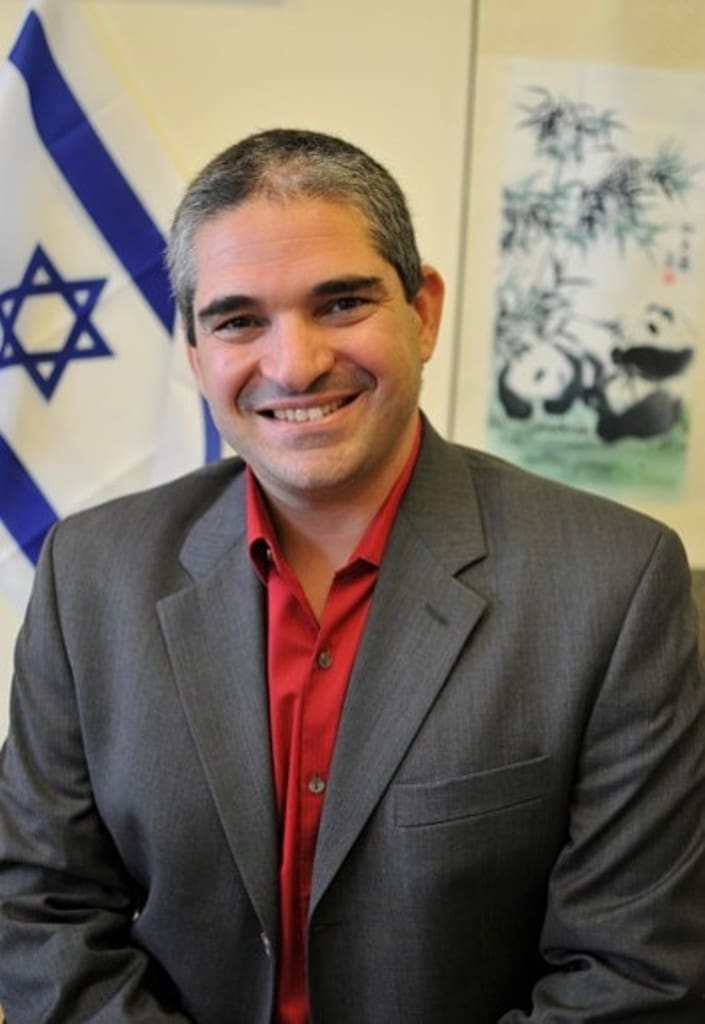 A man in a suit and tie smiling for the camera.