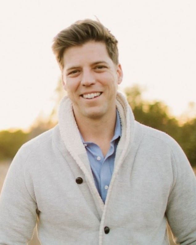 A man in a white jacket smiling for the camera.