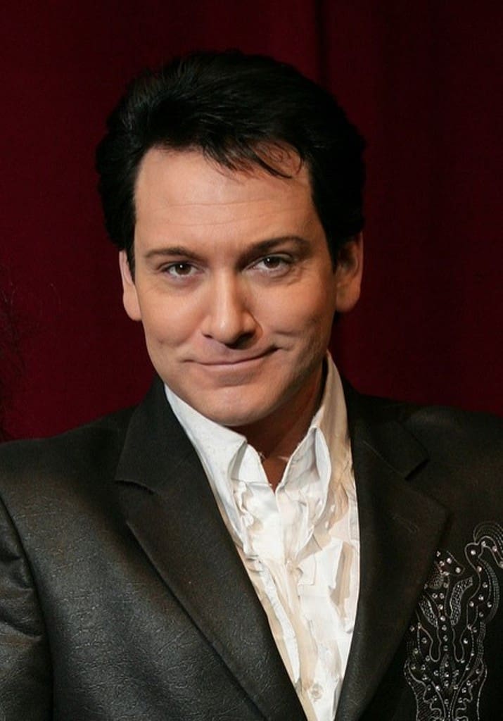 A man in a suit and tie smiling for the camera.