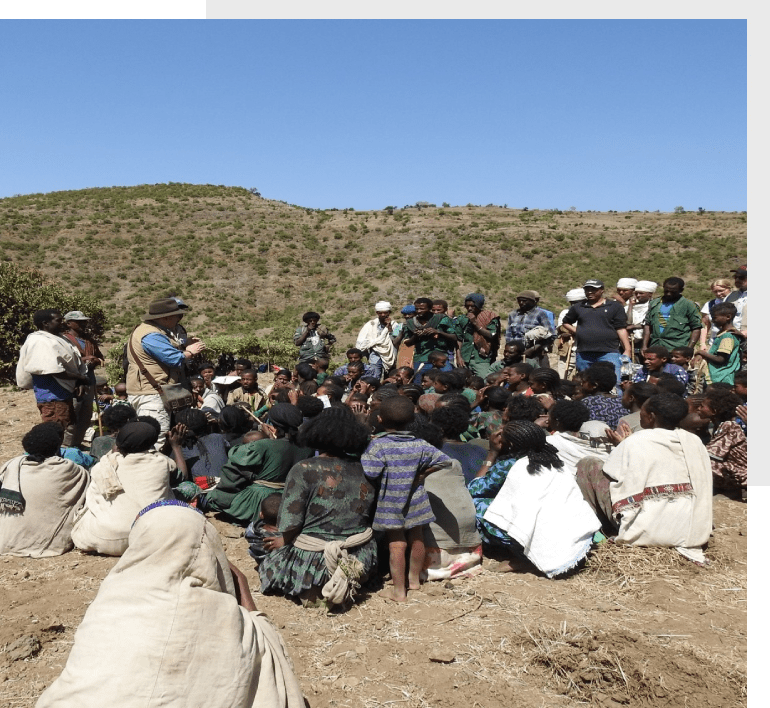 A group of people sitting on top of a dirt hill.