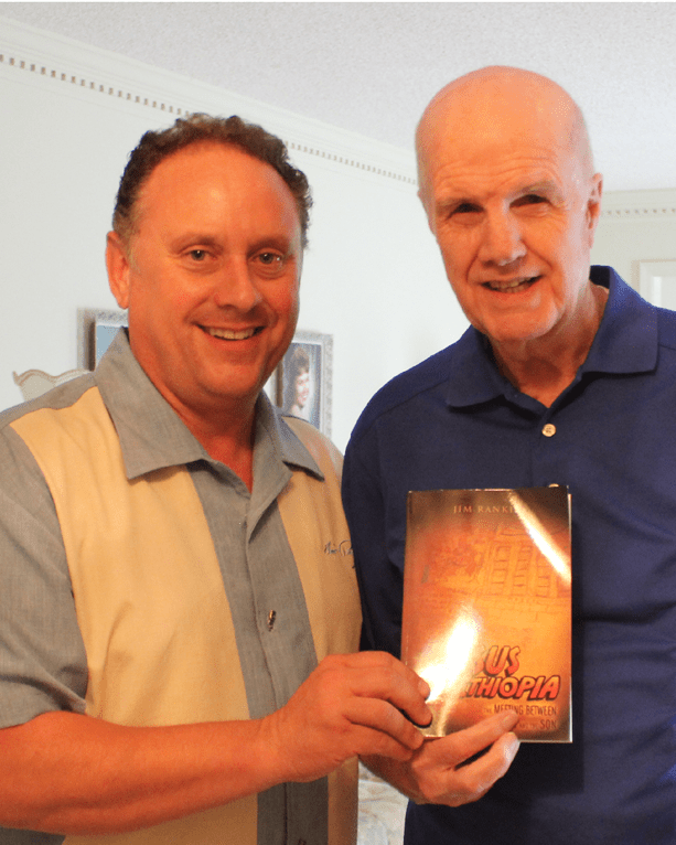 Two men holding a book in front of each other.