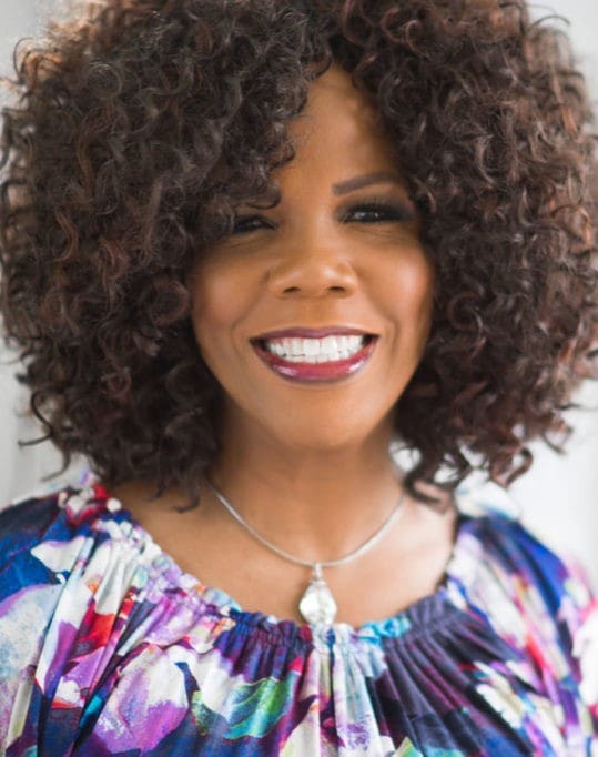 A woman with curly hair and a necklace.